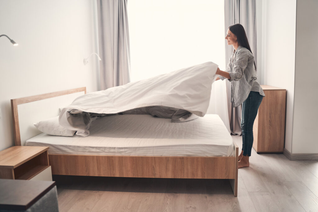 Bonjour. Une jeune fille brune ravie exprime sa positivité en se tenant en position semi-assise près de son lit.