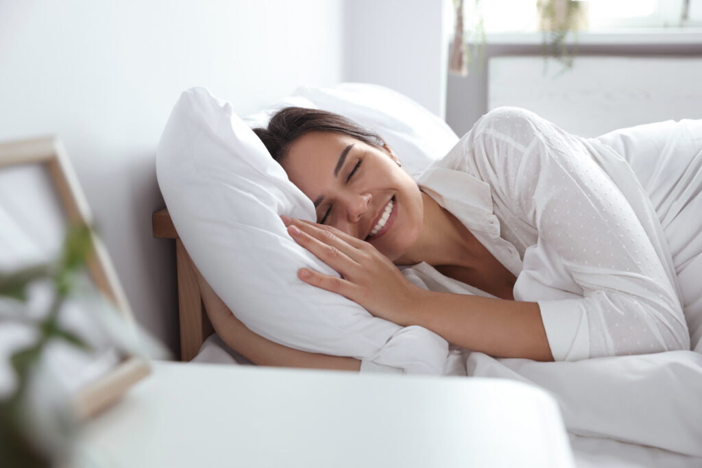 Jeune femme heureuse allongée sur un oreiller moelleux dans son lit à la maison
