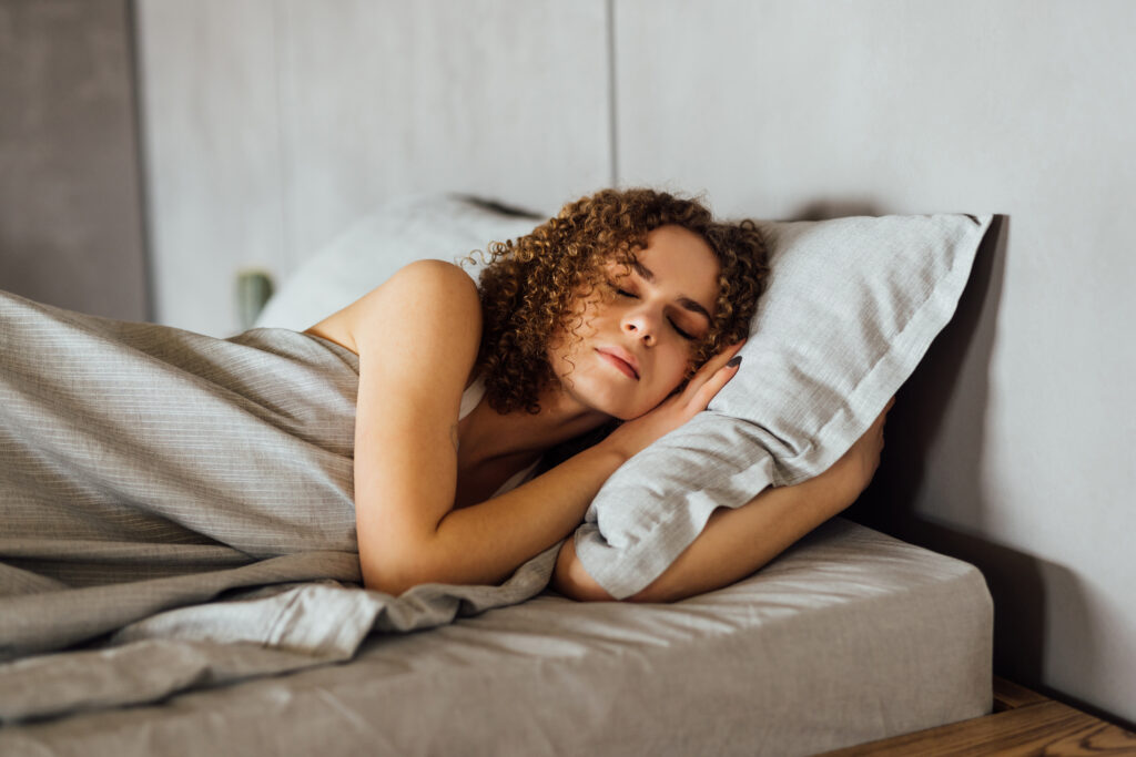 Jeune femme dormant sur un oreiller blanc dans son lit