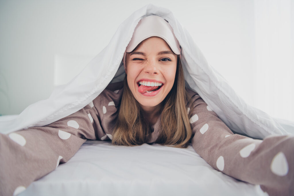 Une jeune femme joyeuse en pyjama sur un matelas apres un bon sommeil