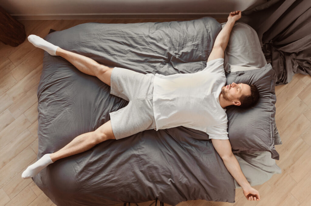 Homme profondément endormi, allongé sur le dos dans son lit, se reposant à la maison. Concept de sommeil réparateur. Vue de dessus.