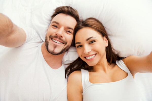 Selfie ! Vue de dessus d'un beau jeune couple amoureux allongé dans son lit et prenant un selfie